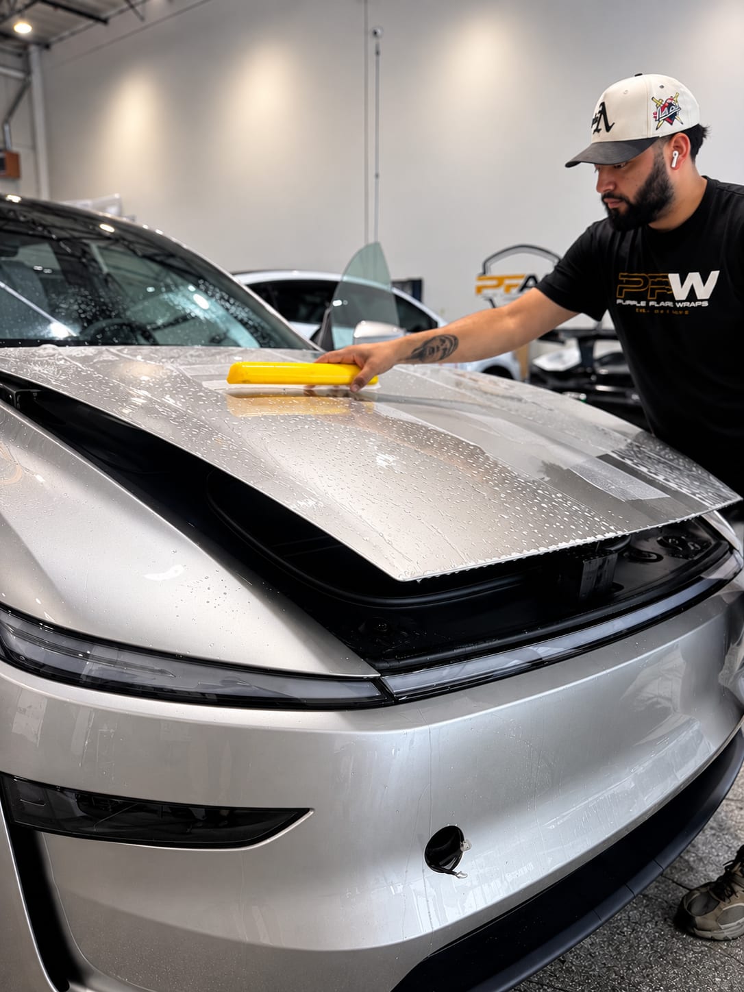 Installer squeegeeing 3M paint protection film onto a full hood