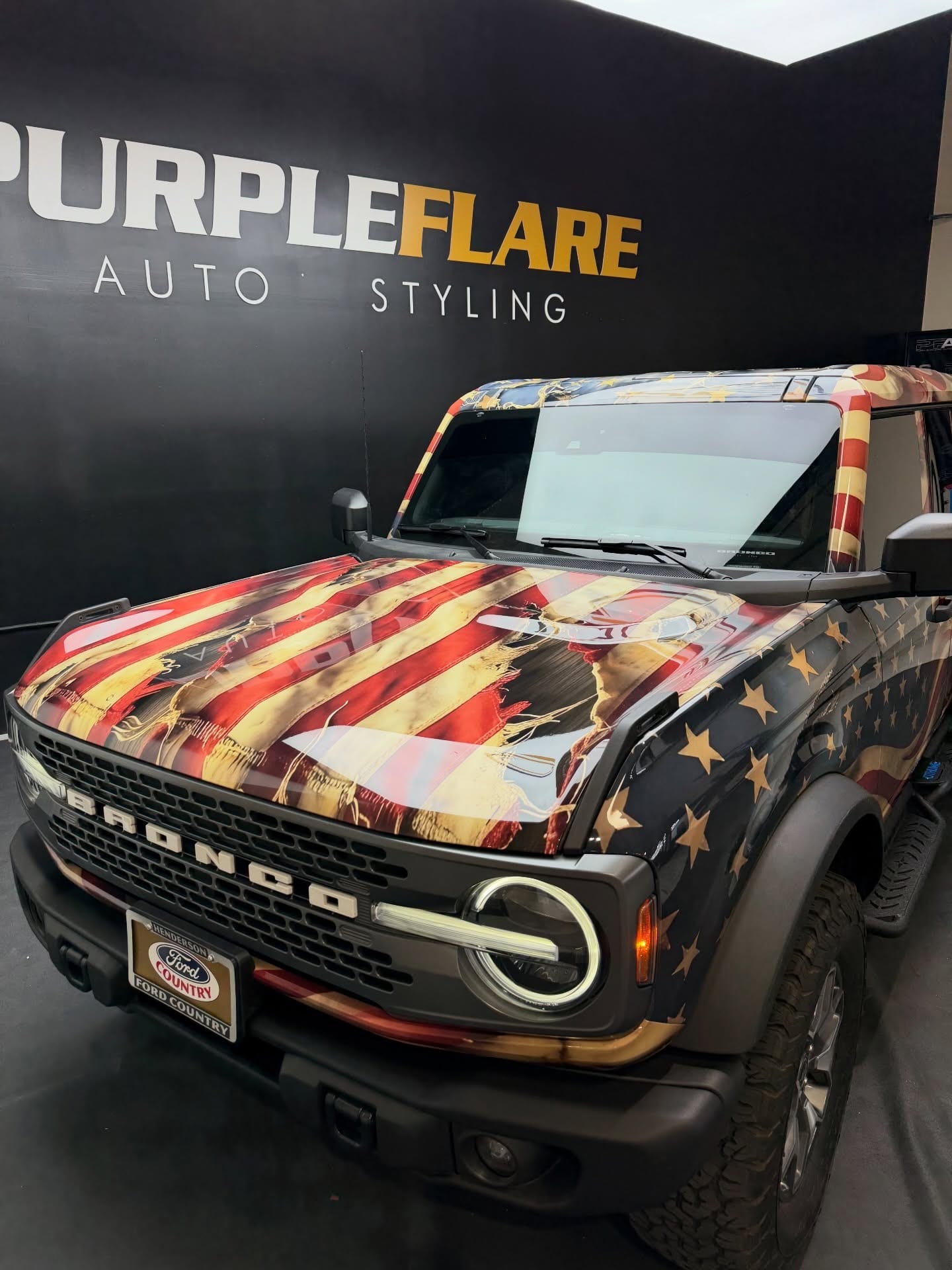 printed ppf wrap — Ford Bronco in a printed American flag PPF wrap in front of the Purple Flare Auto Styling sign